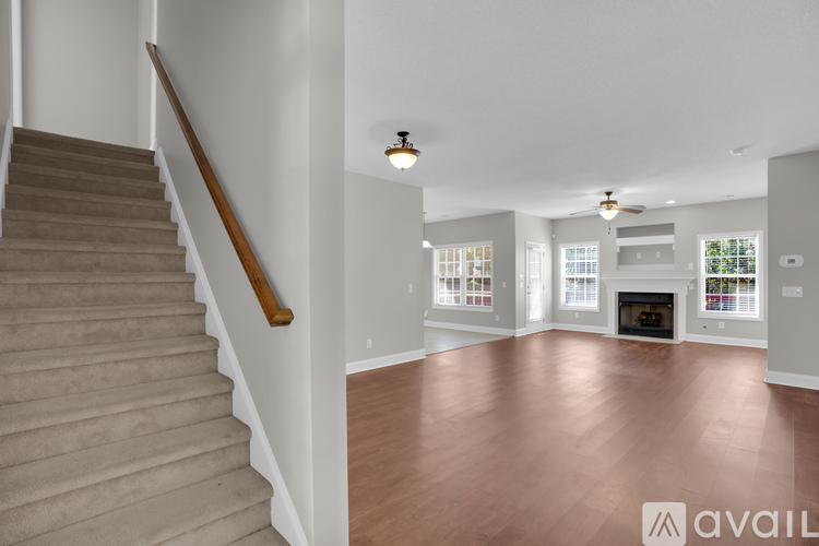 A staircase with a wooden handrail leads up to a bright living room with a fireplace.