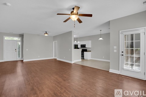 A spacious room with a ceiling fan and wooden flooring.