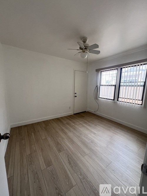A room with a ceiling fan and wooden flooring.