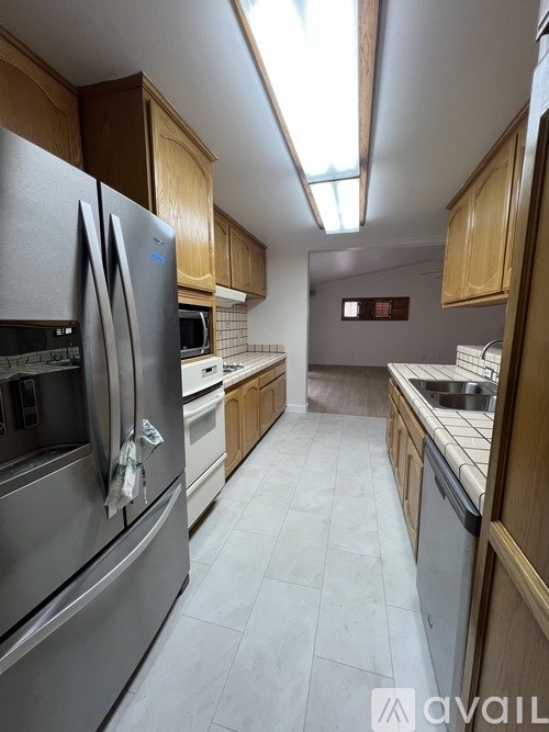 A kitchen with a stainless steel refrigerator and wooden cabinets.