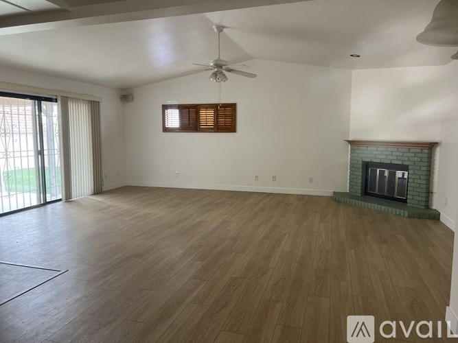 A spacious room with wooden flooring and a fireplace.