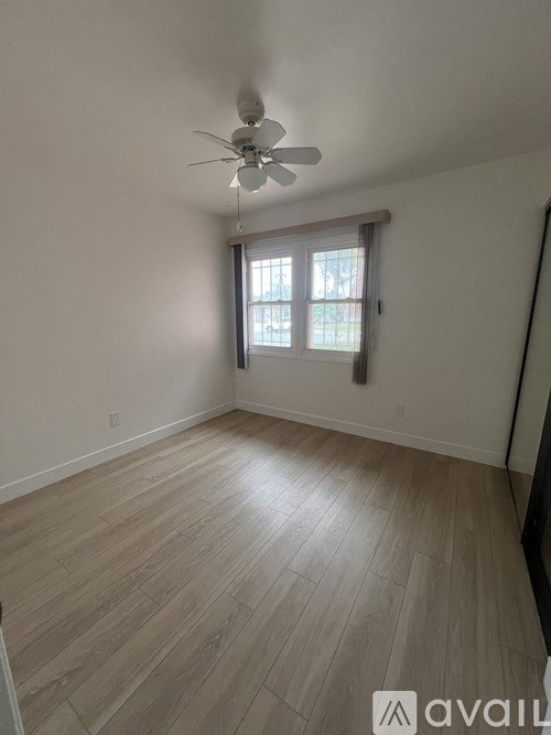 A room with a ceiling fan and a window with blinds.