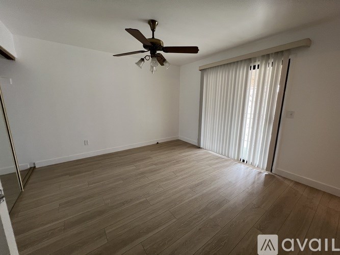 A room with a ceiling fan and sliding glass doors.