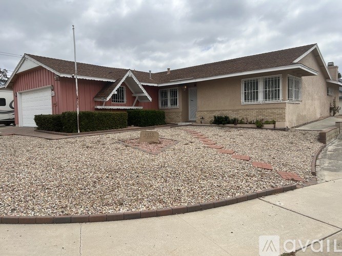 A house with a red garage door and a gravel driveway.