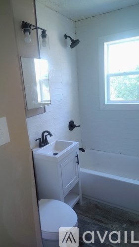 A white bathroom with a toilet, sink, and window.