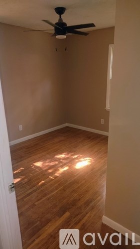 A room with a ceiling fan and wooden flooring.