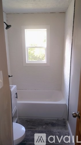 A small bathroom with a toilet, tub, and window.