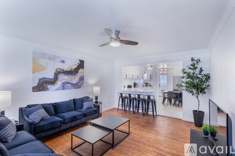 A living room with a blue couch, a coffee table, and a ceiling fan.