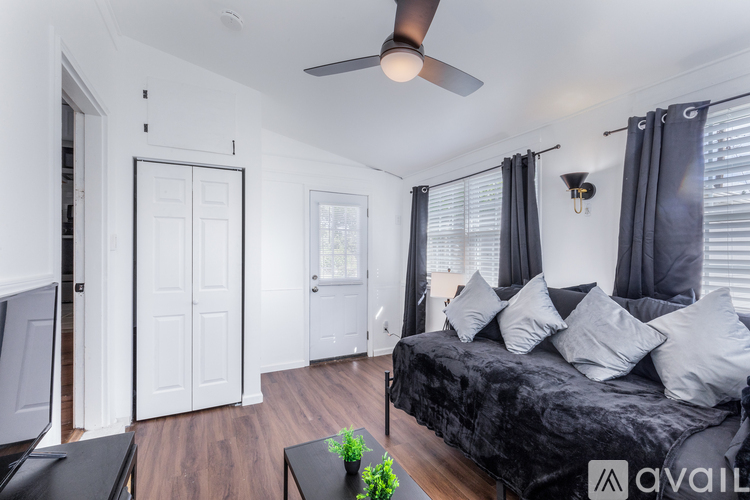 A bedroom with a black bed and a ceiling fan.