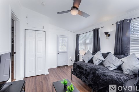 A bedroom with a black bed and a ceiling fan.
