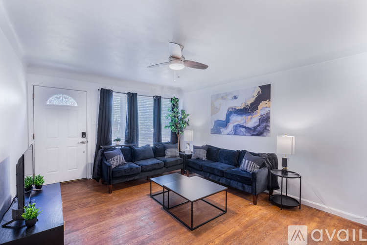 A living room with a black couch and a ceiling fan.