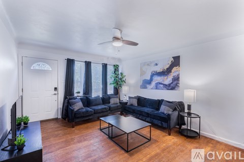 A living room with a black couch and a ceiling fan.