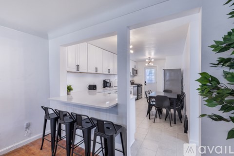 A kitchen with white cabinets and a bar area with black stools.