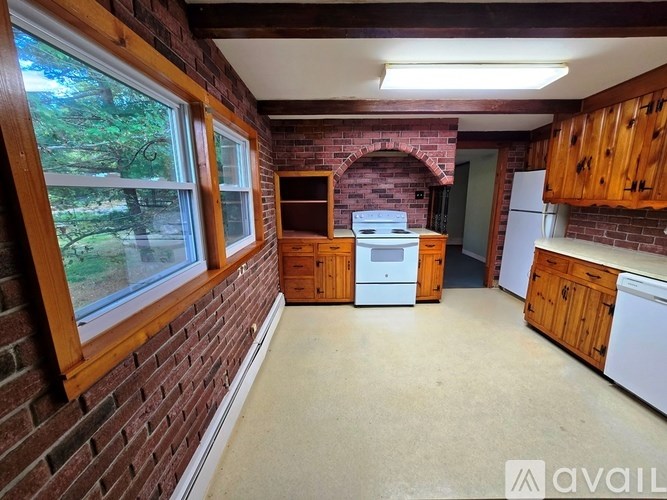 A kitchen with wooden cabinets and a brick wall.
