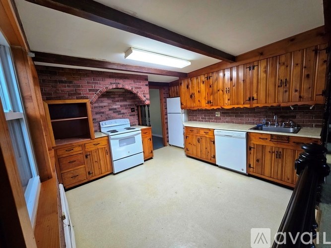 A kitchen with wooden cabinets and a brick wall.