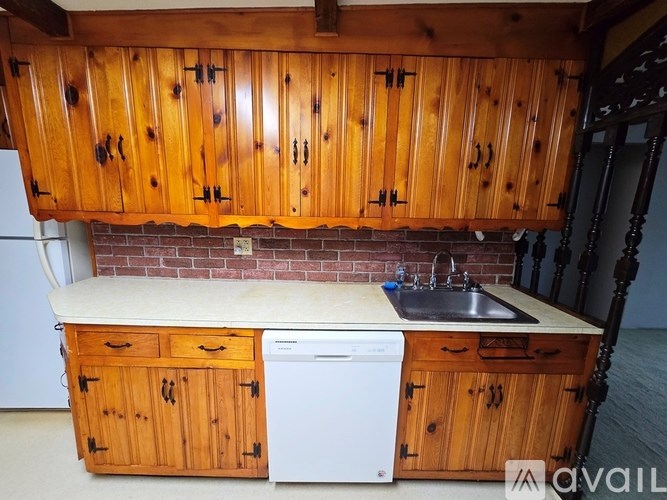 A kitchen with wooden cabinets and a white dishwasher.