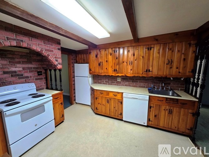 A kitchen with wooden cabinets and a brick wall.