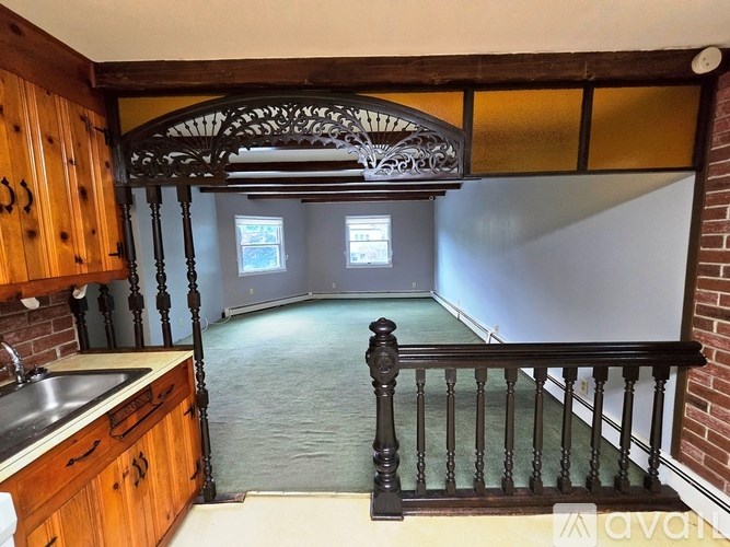 A kitchen with wooden cabinets and a black railing.