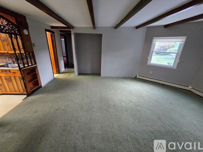 A spacious room with a window and a carpeted floor.