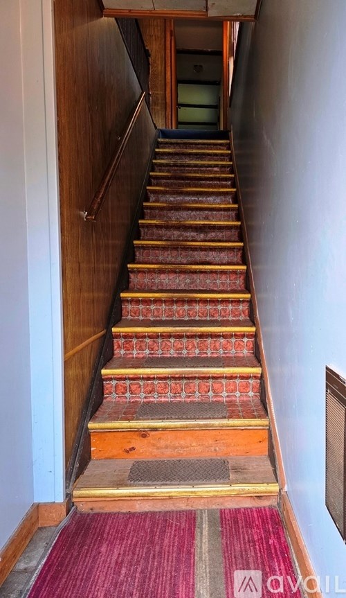 A staircase with a red carpet at the bottom.