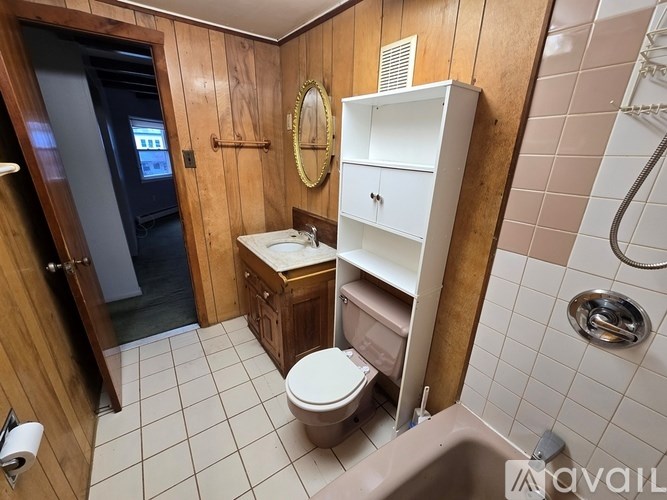 A bathroom with a toilet, sink, and a cabinet.