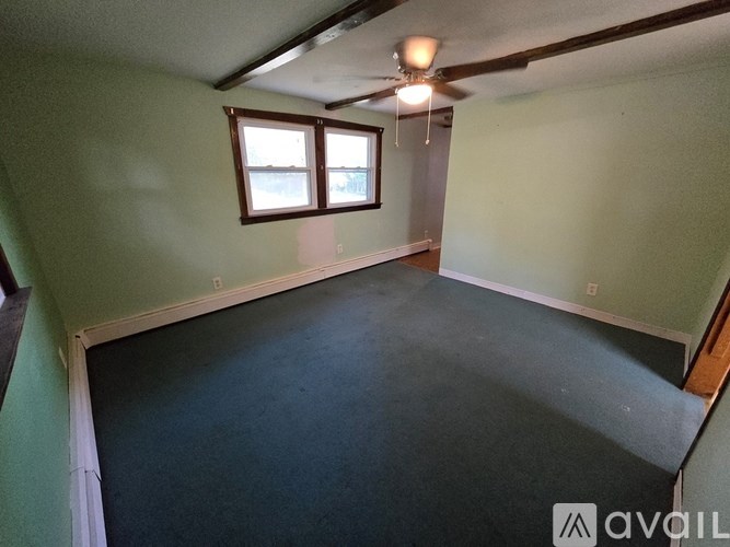 A room with a ceiling fan and two windows.