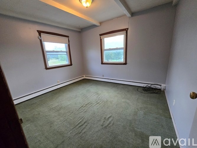 A room with two windows and carpeted floor.