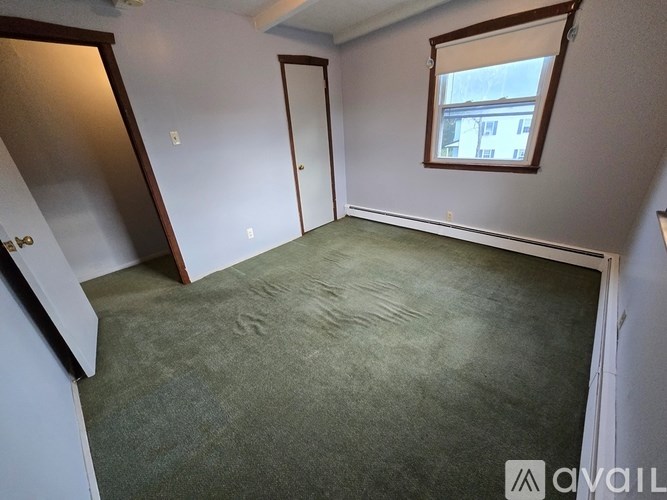 A room with a carpeted floor, a window, and a door.