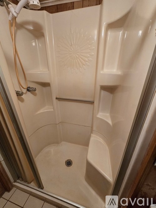 A shower with a tile floor and a tile wall.