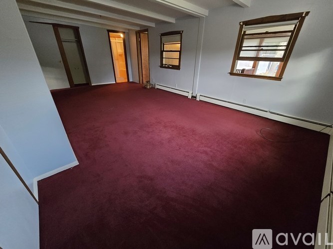 A room with a red carpet and a window with wooden blinds.