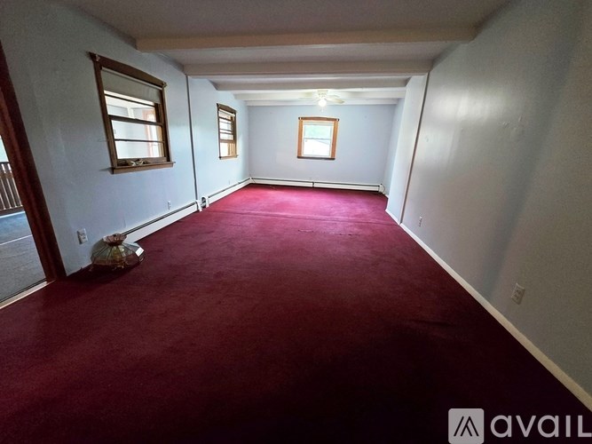 A room with a red carpet and two windows.