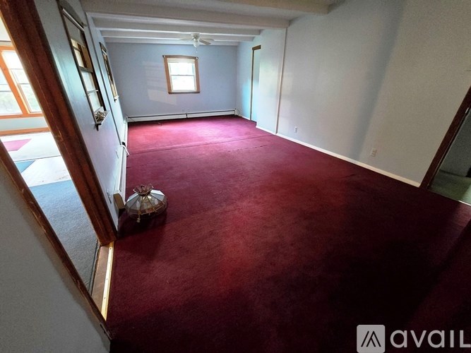 A room with a red carpet and a fan on the wall.