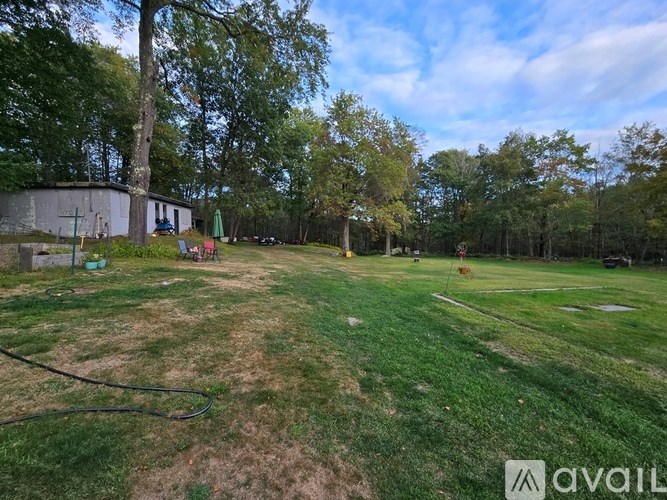 A grassy field with trees and a building in the background.