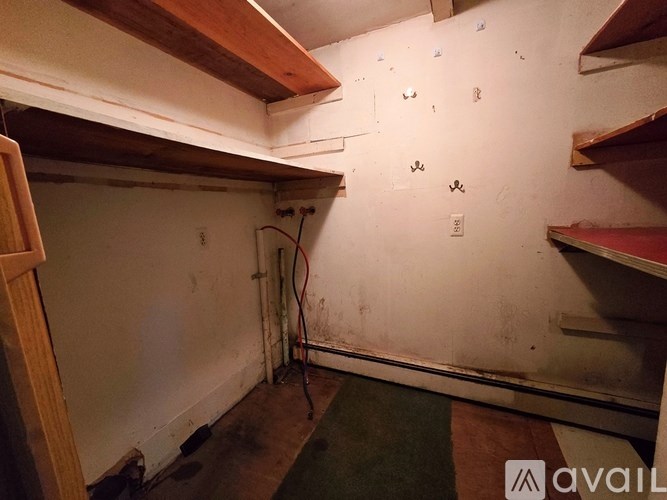 A room with a white wall and a brown shelf.