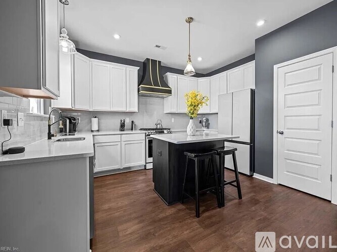 A kitchen with white cabinets and a black island.
