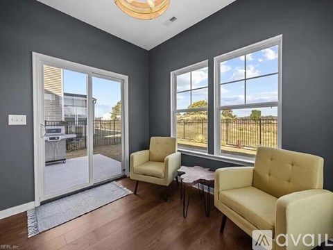 A living room with a yellow chair and a table in front of a window.