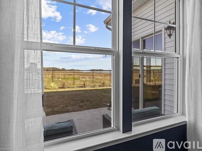 A window with a view of a fenced field.