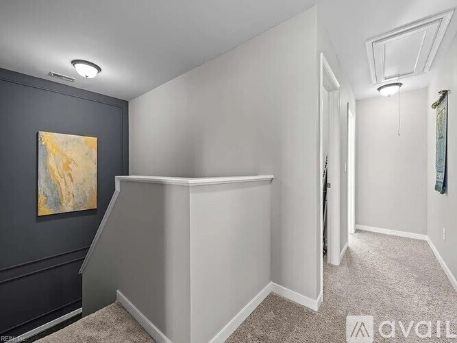 A room with a grey carpet and a painting on the wall.