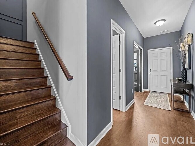 A hallway with a wooden staircase and white doors.