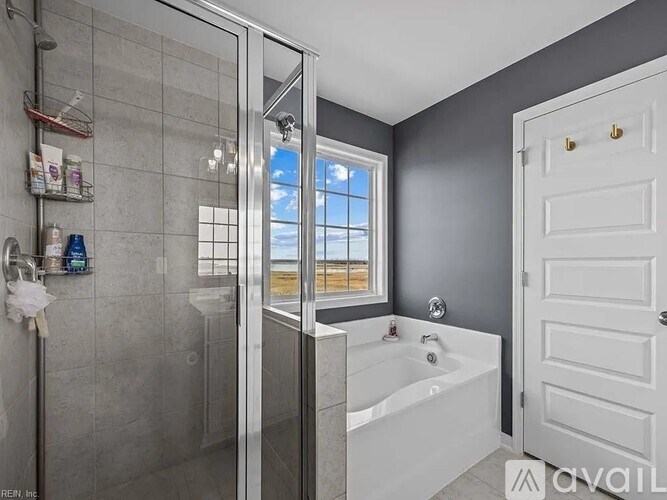 A bathroom with a white tub and a window showing a beach.