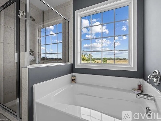 A bathroom with a large window overlooking a field.
