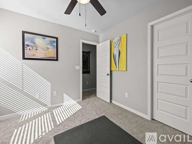 A room with a ceiling fan, two doors, and a painting on the wall.