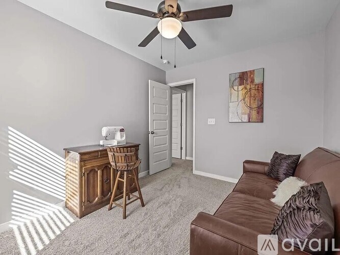 A living room with a brown leather couch and a wooden desk with a sewing machine on it.
