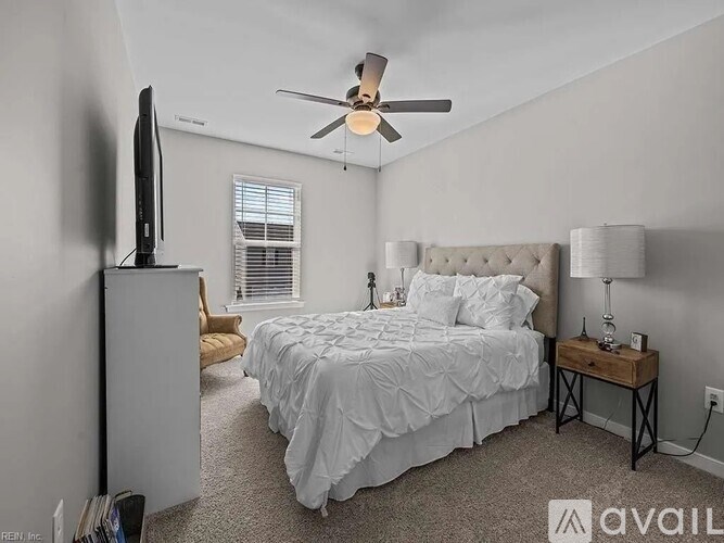 A bedroom with a bed, a ceiling fan, and a television.