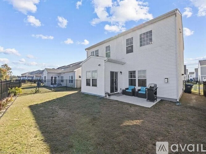 A white house with a black fence and a small lawn in front.