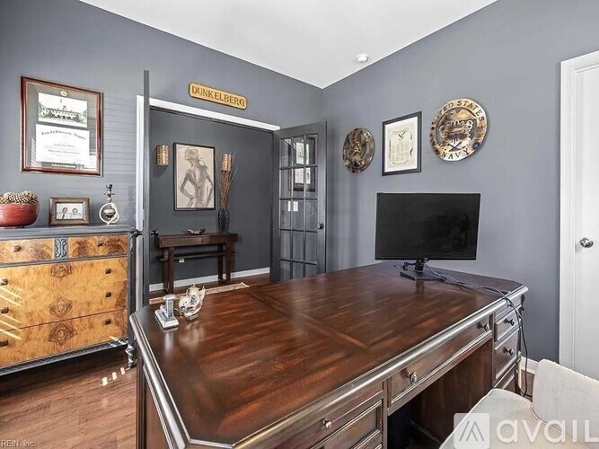 A room with a wooden desk and a tv on the wall.