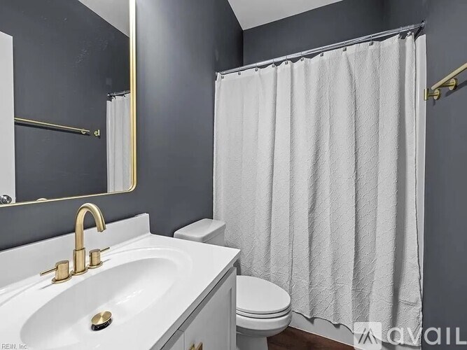 A white sink with gold faucets is in front of a toilet in a bathroom.