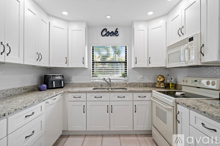 A kitchen with white cabinets and a granite countertop.
