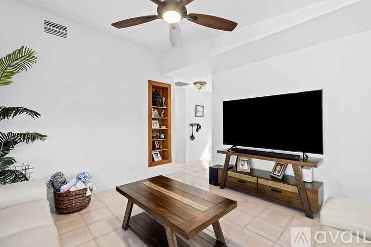 A living room with a wooden table and a flat screen TV.