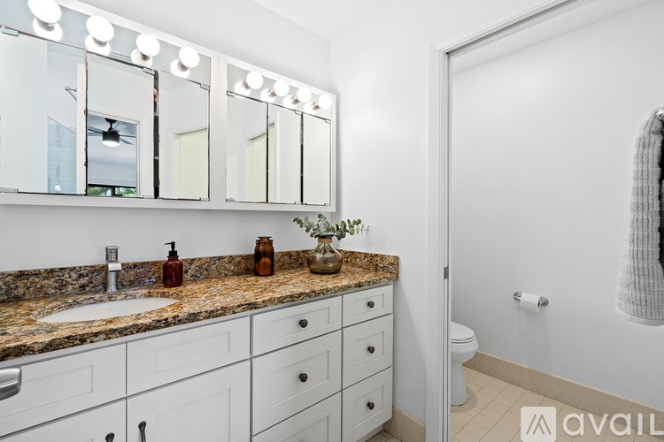 A bathroom with a granite countertop and white cabinets.